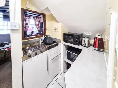 a small kitchen with white cabinets and a microwave at Cosy Cottage in Allonby