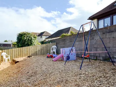a playground with a swing set in a yard at Park View Cottage in Stranraer