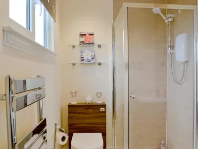 a bathroom with a shower with a toilet and a sink at Park View Cottage in Stranraer