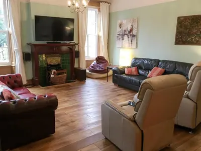 a living room with leather couches and a fireplace at The Moat House in Annan