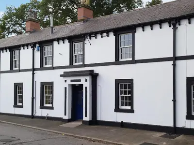 a white building with a blue door on a street at The Moat House in Annan