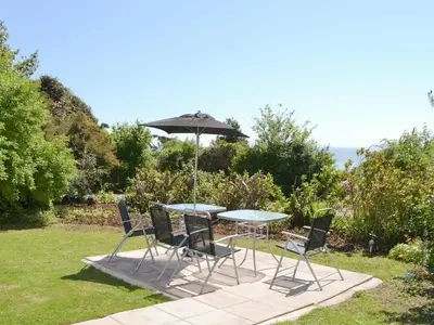 a table and chairs with an umbrella in the grass at Fairview in Rockcliffe
