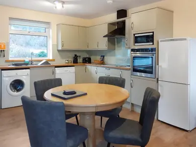 a kitchen with a table and chairs and a white refrigerator at Riverside Cottage in Boreland