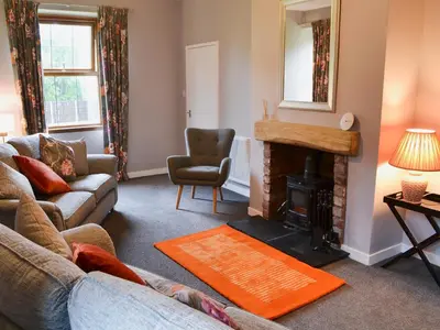 a living room with a couch and a fireplace at Perch Hall Cottage in Dinwoodie Mains