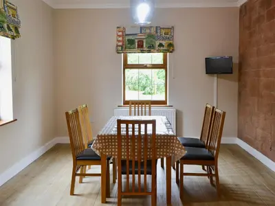 a dining room with a table and four chairs at Perch Hall Cottage in Dinwoodie Mains