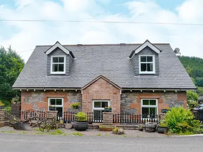 a small stone house with a black roof at The Cottage in Blackwood