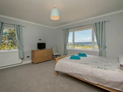a bedroom with a bed and a television and two windows at Quarter Acre House in Challoch