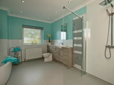 a bathroom with a tub and a toilet and a sink at Quarter Acre House in Challoch