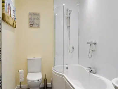 a bathroom with a tub and a toilet and a sink at Hameish Holiday Cottage in Kirkcudbright