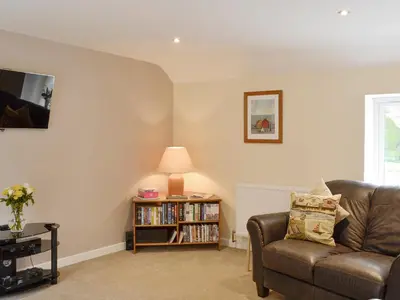 a living room with a couch and a book shelf at Hameish Holiday Cottage in Kirkcudbright