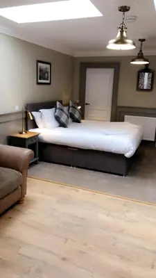 a bedroom with a large bed and a couch at The Huntingdon in Dumfries