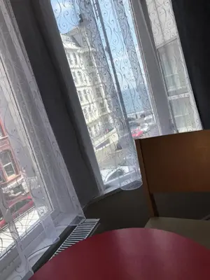 two windows with white curtains and a red table at Glenfaba Guest House in Douglas
