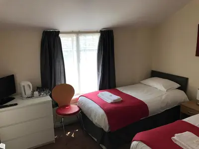 a hotel room with two beds and a window at Glenfaba Guest House in Douglas
