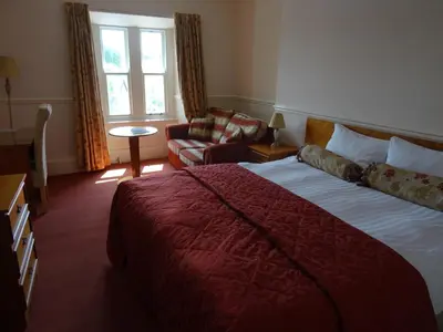 a hotel room with a large bed and a chair at Lutwidge Arms in Holmrook