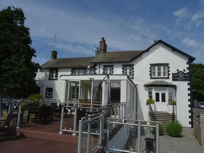 a large white house with a deck in front of it at Lutwidge Arms in Holmrook