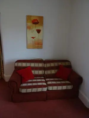 a couch with two red pillows in a living room at Lutwidge Arms in Holmrook