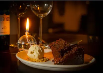 a piece of cake and ice cream on a plate with a candle at The Red Admiral Gosforth CA20 1BP in Seascale