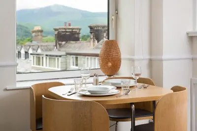 a table with glasses and a plate on it in front of a window at Balmoral Apartment in Keswick