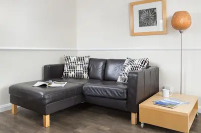 a black leather couch and a coffee table in a living room at Balmoral Apartment in Keswick