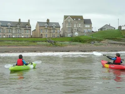 two people in kayaks on a river with houses at Bailey Ground Hotel in Seascale