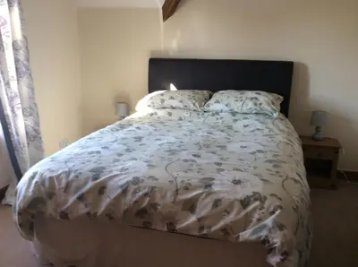 a bedroom with a large bed with a floral comforter at St Matthews cottages in Allonby