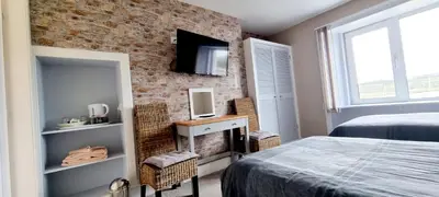 a bedroom with a bed and a tv on a brick wall at The Mariner Hotel in Kippford