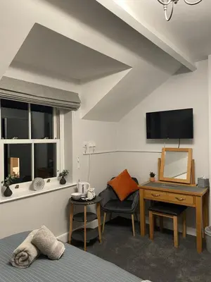 a bedroom with a bed and a desk and a television at Rivendell Guest House in Keswick