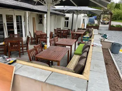 a patio with wooden tables and benches and chairs at The Bridge Inn in Holmrook