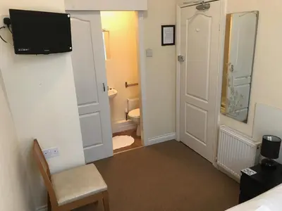 a bathroom with a toilet and a television on a wall at The Island & Fairfield in Douglas