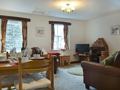 a living room with a table and chairs and a tv at Latrigg View in Keswick
