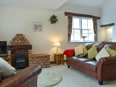 a living room with a leather couch and a fireplace at Latrigg View in Keswick