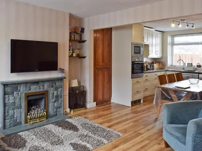 a living room with a fireplace with a flat screen tv at Saddleback in Keswick