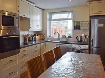 a kitchen with a table with chairs and a refrigerator at Saddleback in Keswick