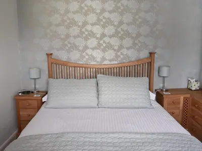a bedroom with a bed and two night stands with lamps at Saddleback in Keswick