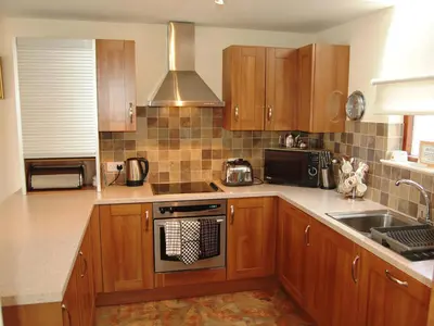 a kitchen with wooden cabinets and a stove top oven at Topsey Turvey in Keswick