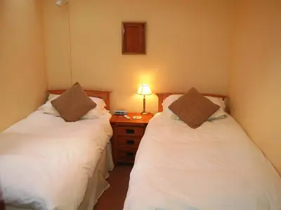 a bedroom with two beds and a night stand with a lamp at Topsey Turvey in Keswick