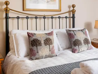 a bed with two pillows and a picture on the wall at Bunbury Cottage in Keswick