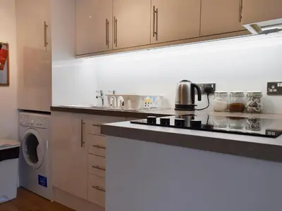 a kitchen with a stove top oven next to a washing machine at Royal Views in Keswick