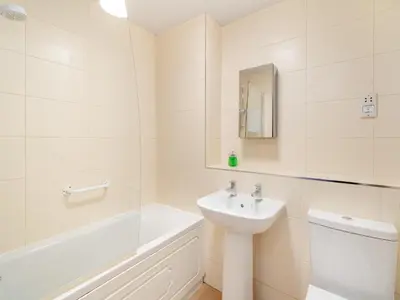 a white bathroom with a sink and a bath tub at Olivet - Hewetson Court in Keswick