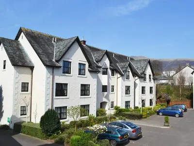 a large white house with cars parked in a parking lot at Beech Nut in Keswick