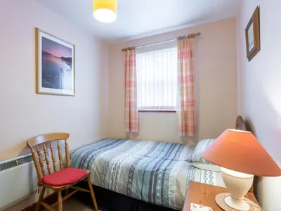 a bedroom with a bed and a chair and a window at Beech Nut in Keswick