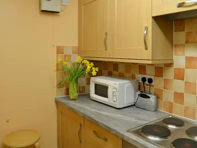 a kitchen counter with a microwave and a vase of flowers at Beech Nut in Keswick