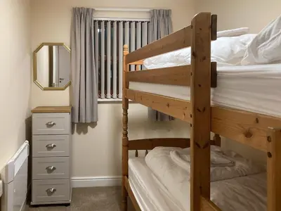 a bedroom with two bunk beds and a mirror at Ashbrooke- Hewetson Court in Keswick