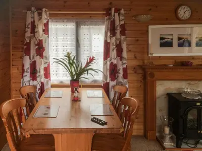 a dining room with a wooden table and a fireplace at Fell View Lodge in Keswick