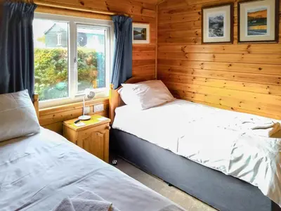 two beds in a wooden room with a window at Bewick Lodge in Keswick