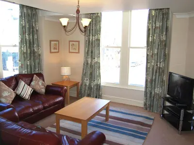 a living room with a leather couch and a tv at Brundholme in Keswick
