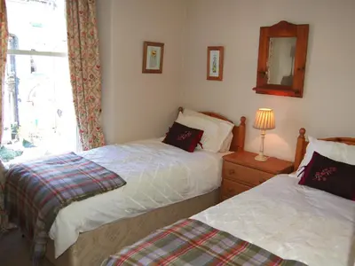 a bedroom with two beds and a mirror and a window at Brundholme in Keswick