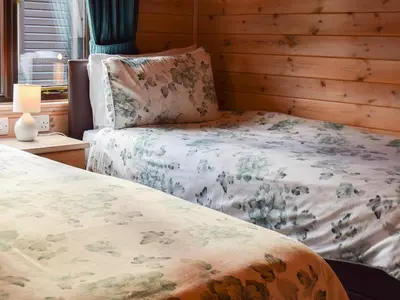 a bedroom with a bed with a floral bedspread at Whinny Brow - Burnside Park in Keswick