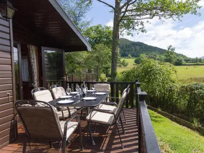 a table and chairs on a deck with a view of a field at Whiteside Lodge At Burnside Park in Keswick