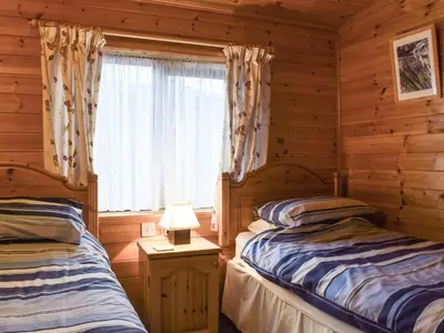 two beds in a log cabin with a window at Whiteside Lodge At Burnside Park in Keswick